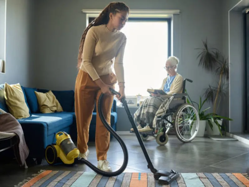 Support worker vacuuming a carpet in a participant's living room